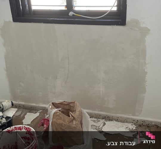 עבודת שפכטל והחלקת קיר פנים ליד חלון במהלך שיפוץ